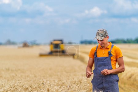 Téléchargez les photos : Jeune agriculteur se tient dans le champ de blé et souriant. - en image libre de droit