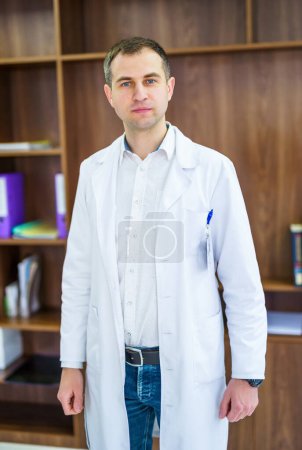 Serious handsome doctor standing. Young medical specialist.