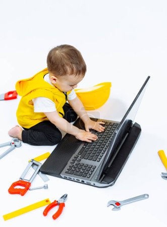 A young child is sitting on the floor in front of a laptop, typing on the keyboard. The scene is playful and lighthearted