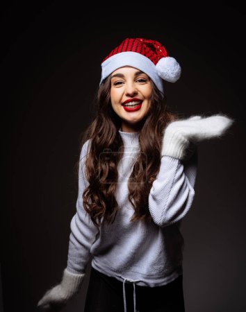 Téléchargez les photos : Une femme au chapeau rouge et au pull blanc sourit et pose pour une photo. L'image a une humeur festive et joyeuse - en image libre de droit