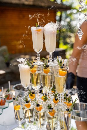 Téléchargez les photos : A stack of champagne glasses with fruit garnishes on top. The glasses are arranged in a pyramid shape - en image libre de droit
