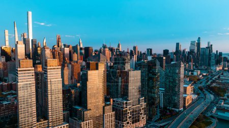 Téléchargez les photos : Skyline of New York at the waterfront of the East River in New York, the USA. Drone approaching the scenery of metropolis at sunset. - en image libre de droit