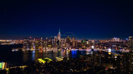 Téléchargez les photos : Éloignement d'une vue spectaculaire de New York, États-Unis sur le front de mer de l'East River. Skyline de la métropole la nuit. Perspective aérienne. - en image libre de droit