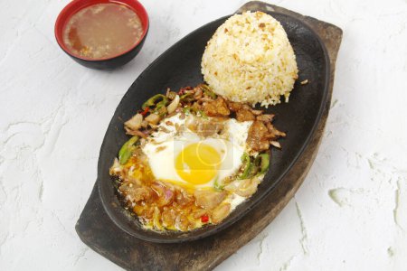 Photo of freshly cooked Filipino food called Sizzling Sisig or chopped pork's face skin served with fried rice.