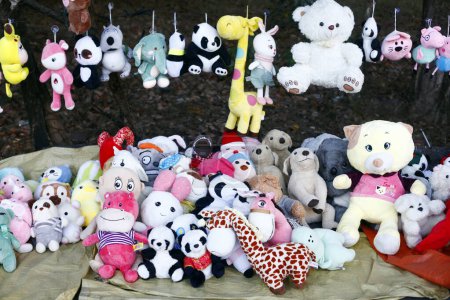 Photo of stuffed animal toys are displayed for sale along a sidewalk.