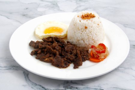Photo of freshly cooked Filipino food called Tapsilog or beef tenders served with fried rice and egg.