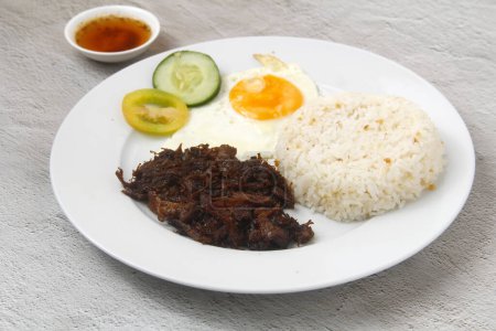 Photo of freshly cooked Filipino food called Tapsilog or beef tenders served with fried rice and egg.