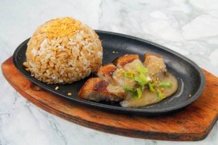Photo du ventre de porc frit fraîchement cuit servi avec riz à l'ail et sauce.