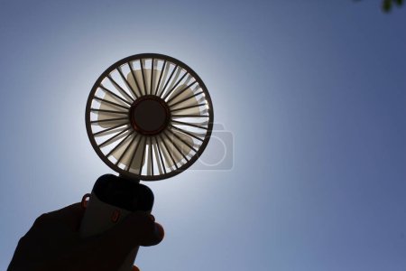 Photo of hand holding a portable rechargeable electric fan.
