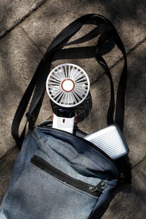 Foto eines tragbaren wiederaufladbaren elektrischen Ventilators in einer Tasche.