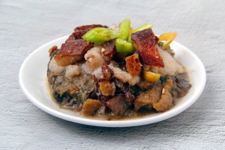 Foto von frisch gekochten philippinischen Gericht namens Laing mit Lechon oder Taro in Kokosmilch mit knusprigem Schweinefleisch garniert gekocht.