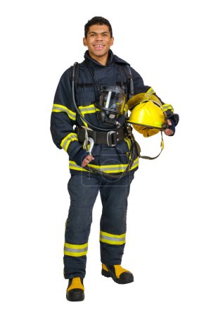 Foto de Joven bombero afroamericano sonriente de cuerpo completo con uniforme ignífugo sostiene el casco amarillo en las manos y mirando a la cámara, aislado sobre fondo blanco - Imagen libre de derechos