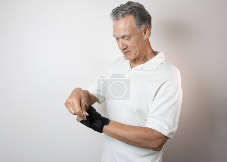 Foto de Hombre mayor con un brazalete en la mano izquierda y la muñeca para controlar el dolor - Imagen libre de derechos