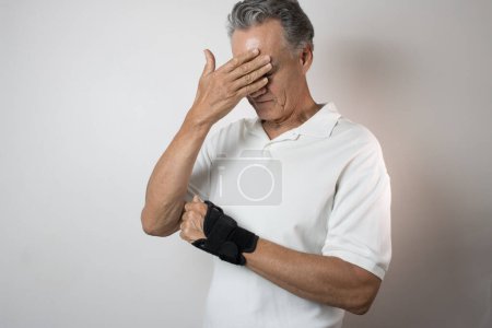 Photo for Senior Man wearing a wrist brace on his left hand and wrist for pain management - Royalty Free Image