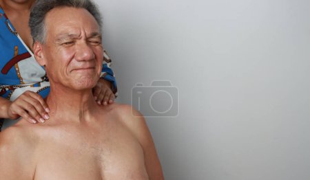 Photo for Older Mature Man having a massage on his upper back and neck for pain relief with a Percussion Massage Gun - Royalty Free Image