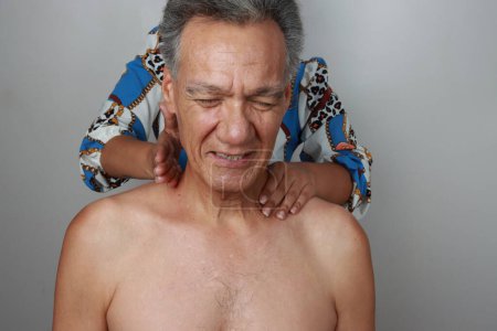 Photo for Older Mature Man having a massage on his upper back and neck for pain relief with a Percussion Massage Gun - Royalty Free Image
