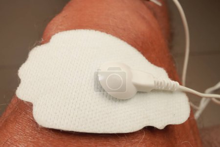 Homme utilisant un masseur électro thérapie ou une unité de dix sur son genou