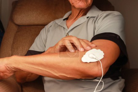 Man using an Electro Therapy Massager or Tens Unit on his elbow