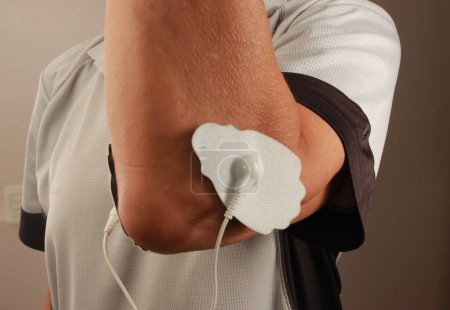 Man using an Electro Therapy Massager or Tens Unit on his elbow
