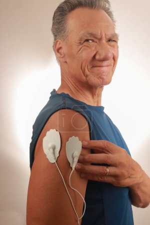 Mann mit einem Elektrotherapie-Massagegerät oder einer Zeheneinheit auf seinem Deltamassagier zur Schmerzlinderung von Muskeln und Gelenken 