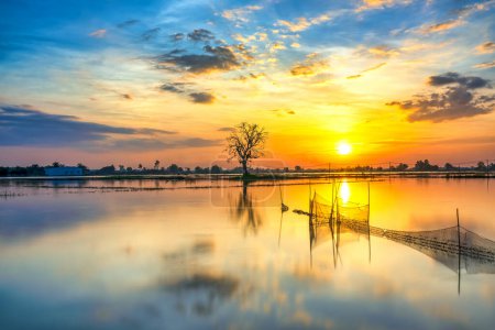 Téléchargez les photos : Coucher de soleil le long de la rivière inondé campagne marécageuse que le soleil vers le bas horizon vraiment dramatique fin d'une journée ensoleillée. - en image libre de droit