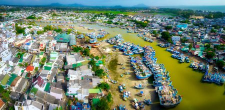 Téléchargez les photos : Village de pêcheurs de La Gi vu d'en haut avec des centaines de bateaux ancrés le long des deux rives de la rivière pour éviter les tempêtes près de l'estuaire, c'est aussi un grand port de pêche fournissant des fruits de mer dans le centre du Vietnam - en image libre de droit