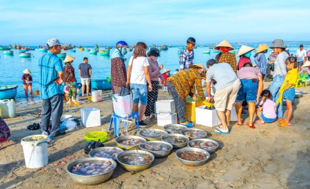 Téléchargez les photos : Phan Thiet, Vietnam - 12 février 2023 : Des gens se sont rassemblés à l'intérieur de la vente de poisson panier, pêcheurs à l'aviron acharnés amenés à terre village de pêcheurs à Phan Thiet, Vietnam - en image libre de droit