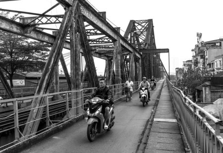 Foto de Hanoi, Vietnam - 6 de mayo de 2024: El tráfico de personas en las vías férreas que conducen sobre el puente Long Bien, Está construido a principios del siglo XX fue diseñado por Gustave Eiffel en Hanoi, Vietnam - Imagen libre de derechos