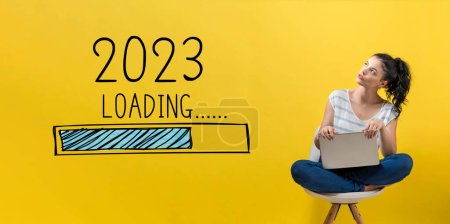 Téléchargez les photos : Chargement de la nouvelle année 2023 avec une jeune femme utilisant un ordinateur portable - en image libre de droit