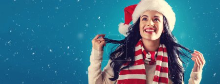 Photo for Happy young woman with a Santa hat in a snowy night - Royalty Free Image