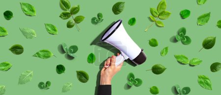 Photo for Person holding a megaphone with green leaves - flat lay - Royalty Free Image