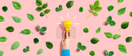 Photo for Person holding a light bulb with green leaves - Royalty Free Image