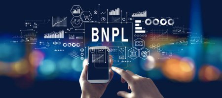 Photo for BNPL - Buy Now Pay Later theme with person using a smartphone in a city at night - Royalty Free Image