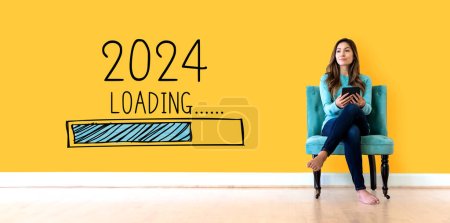Téléchargez les photos : Chargement de la nouvelle année 2024 avec une jeune femme tenant une tablette - en image libre de droit
