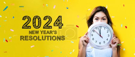 Foto de 2024 Resoluciones de Año Nuevo con una mujer joven sosteniendo un reloj que muestra casi 12 - Imagen libre de derechos