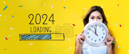 Téléchargez les photos : Chargement de la nouvelle année 2024 avec jeune femme tenant une horloge montrant près de 12 - en image libre de droit