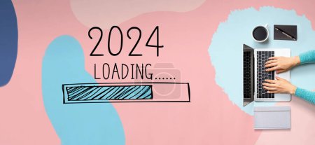 Téléchargez les photos : Chargement de la nouvelle année 2024 avec une personne utilisant un ordinateur portable - en image libre de droit