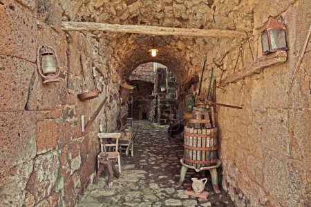 Photo for Celleno, Viterbo, Lazio, Italy: underpass in the ancient abandoned village with an old wine press and tools that recall the rural traditional works - Royalty Free Image