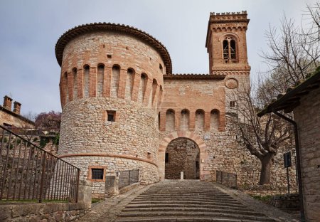 Corciano, Perugia, Umbría, Italia: la puerta de la ciudad Porta di Santa Maria con la torre redonda y el campanario de la iglesia
