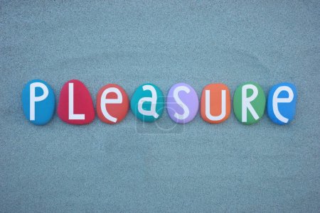 Pleasure, creative word composed with hand painted multi colored stone letters over green sand