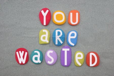 Photo for You are wasted, creative t-shirt design text composed with hand painted multi colored stone letters over green sand - Royalty Free Image