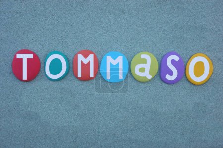 Tommaso, masculine given name composed with hand painted multi colored stone letters over green sand