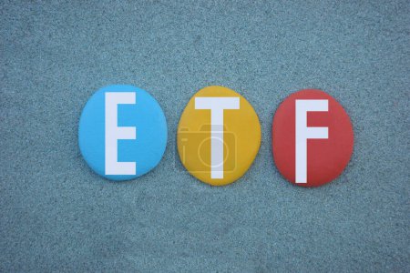 Foto de ETF, Exchange Traded Funds, signo creativo compuesto por letras de piedra multicolor pintadas a mano sobre arena verde - Imagen libre de derechos