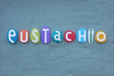 Celebration of Eustachio, Italian masculine first name composed with hand painted multi colored stone letters over green sand
