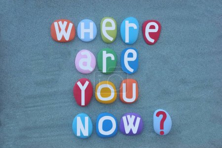 Where are you now, usual question composed with hand painted multi colored stone letters over green sand