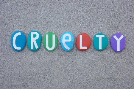 Photo for Cruelty, the quality of being cruel and causing tension or annoyance, word composed with hand painted multi colored stone letters over beach sand - Royalty Free Image
