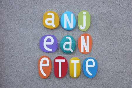 Anjeanette, feminine given name composed with hand painted multi colored stone letters over beach sand