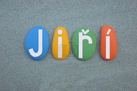 Jiri, most common Czech boy name composed with hand painted multi colored stone letters over green sand