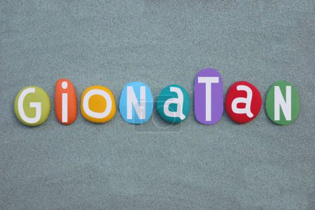 Gionatan, masculine italian given name composed with hand painted multi colored stone letters over green sand