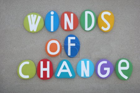 Winds of change, creative slogan composed with hand painted multi colored stone letters over beach sand